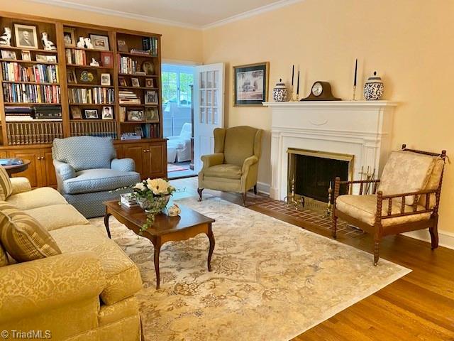305 W Avondale Dr, Greensboro, NC 27403 - sitting room with wood finished floors, ornamental molding, a fireplace with flush hearth, and baseboards