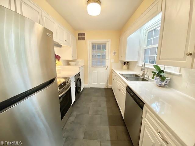 305 W Avondale Dr, Greensboro, NC 27403 - kitchen with stainless steel appliances, a sink, white cabinetry, and light countertops