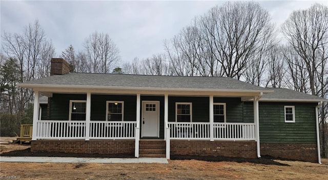 single story home with covered porch, roof with shingles, and a chimney