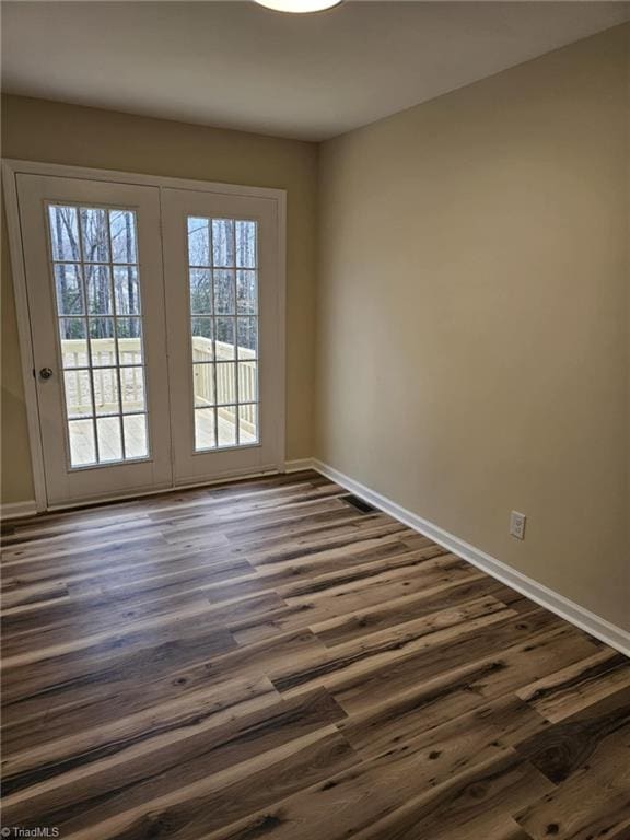 empty room with baseboards and dark wood-type flooring