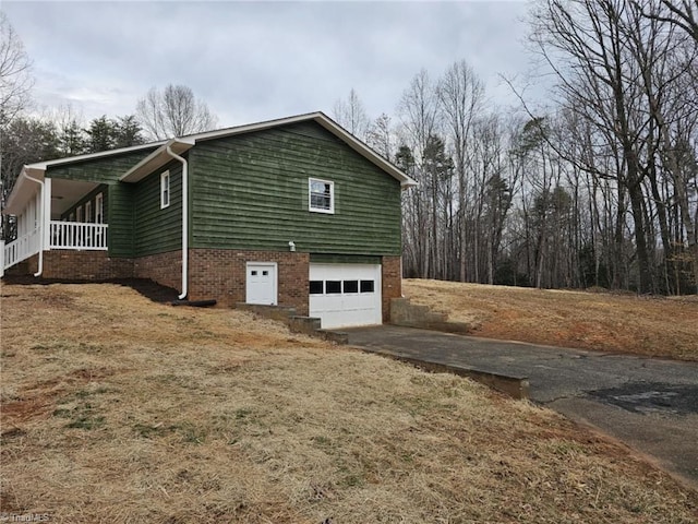 view of property exterior with driveway, an attached garage, and a porch