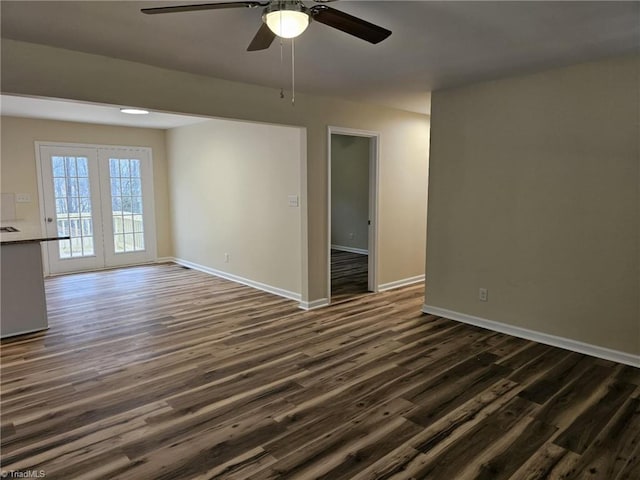 empty room featuring a ceiling fan, dark wood-style flooring, and baseboards