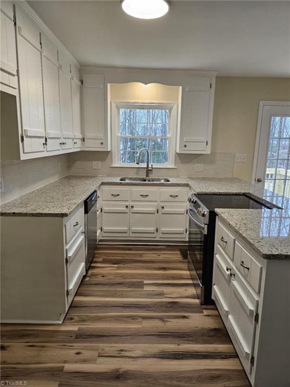 kitchen with stainless steel appliances, dark wood-type flooring, a peninsula, a sink, and white cabinets