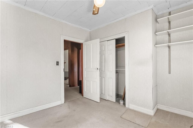 unfurnished bedroom featuring a closet, ceiling fan, crown molding, and light colored carpet