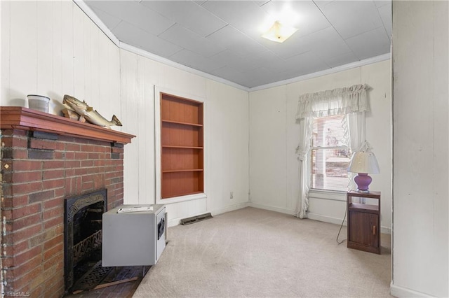 carpeted living room featuring built in features, crown molding, and a brick fireplace