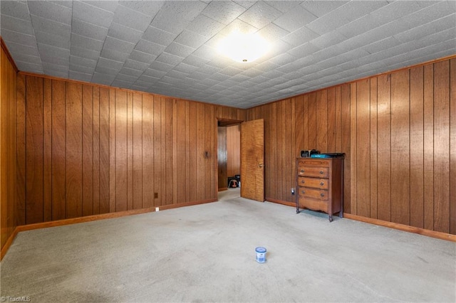 carpeted spare room featuring wood walls