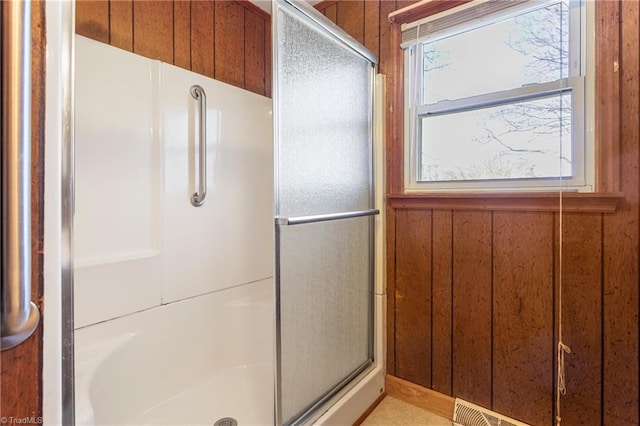 bathroom with wood walls and an enclosed shower