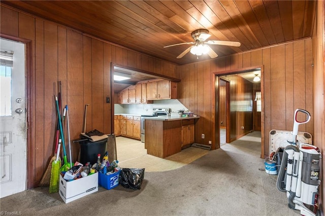 kitchen with stainless steel range with electric stovetop, wood walls, light colored carpet, and kitchen peninsula