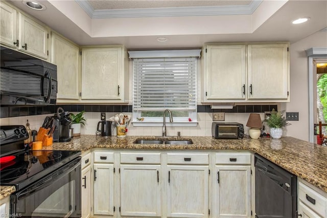 kitchen with a sink, tasteful backsplash, black appliances, and a tray ceiling