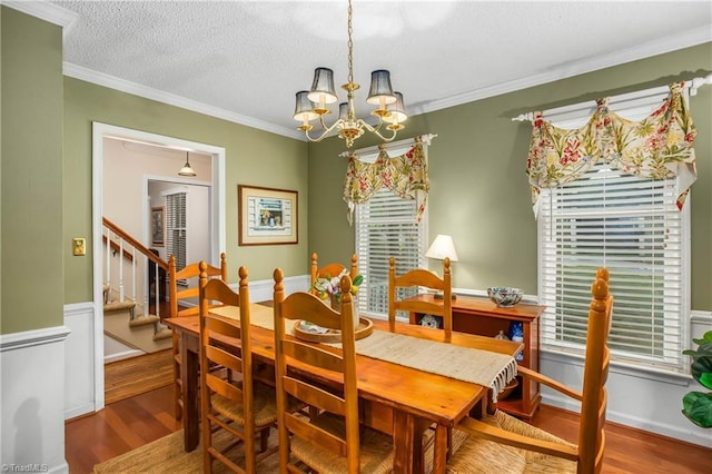 dining space featuring a textured ceiling, wood finished floors, stairway, a notable chandelier, and ornamental molding