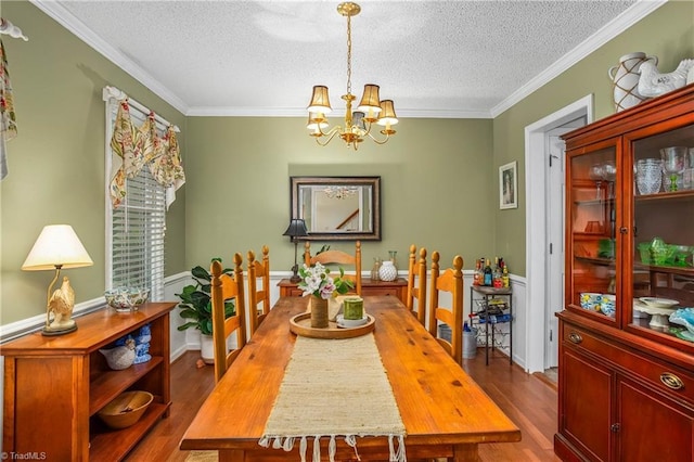 dining space featuring ornamental molding, a textured ceiling, and wood finished floors