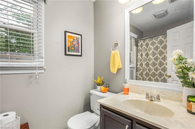 bathroom featuring vanity, a shower with curtain, toilet, and visible vents