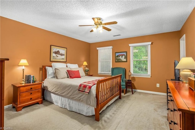 carpeted bedroom featuring baseboards, ceiling fan, a textured ceiling, and visible vents