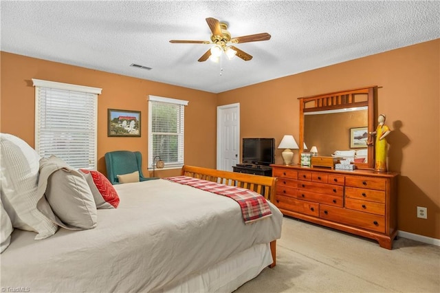 carpeted bedroom featuring a ceiling fan, a textured ceiling, visible vents, and baseboards
