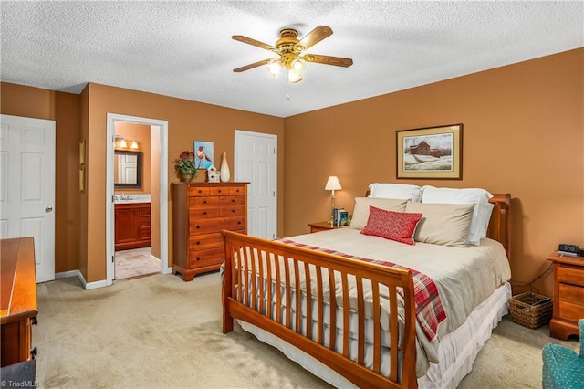 bedroom with connected bathroom, ceiling fan, light carpet, a sink, and baseboards
