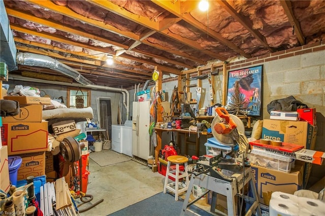 unfinished basement featuring independent washer and dryer and white fridge with ice dispenser