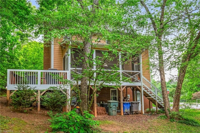 back of property featuring a wooden deck, stairs, a sunroom, and brick siding