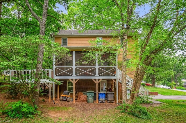 back of house featuring a wooden deck, a sunroom, stairway, and brick siding