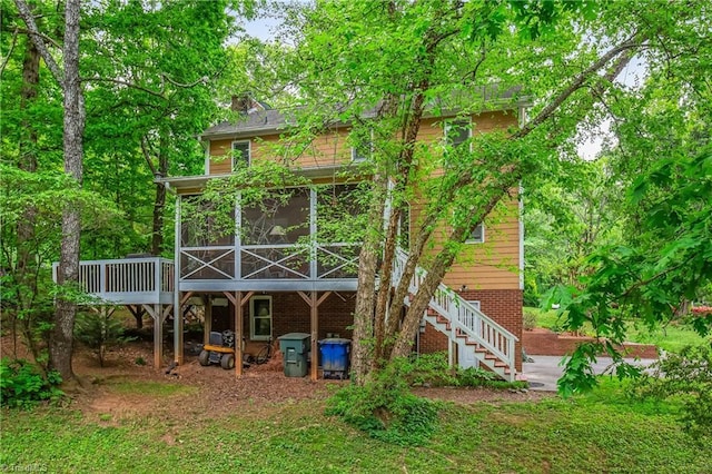 back of house featuring a chimney, stairs, a sunroom, and a wooden deck