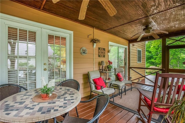 sunroom / solarium featuring outdoor dining area, ceiling fan, and french doors