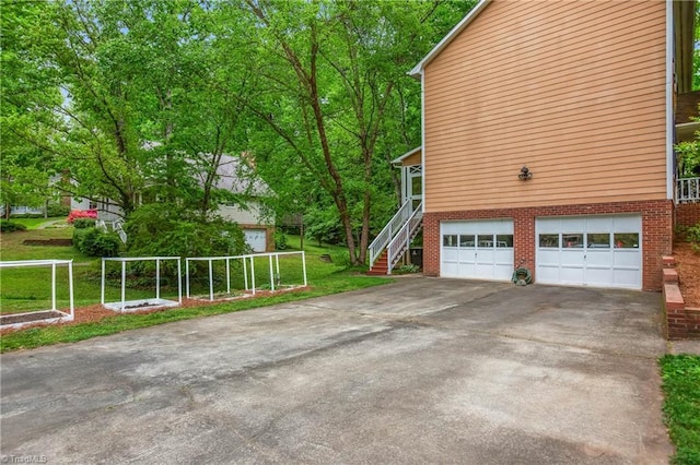 view of home's exterior featuring stairway, brick siding, driveway, and a garage