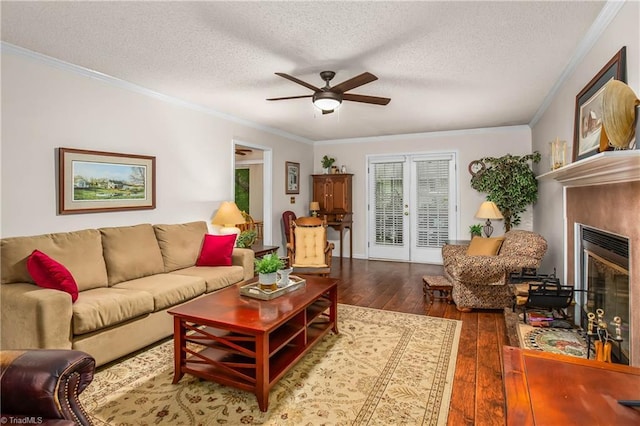 living area featuring a ceiling fan, a textured ceiling, a glass covered fireplace, and hardwood / wood-style floors