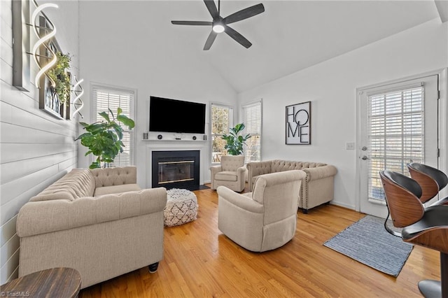 living room featuring a fireplace with flush hearth, plenty of natural light, and wood finished floors