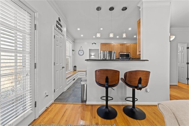 kitchen featuring dark countertops, appliances with stainless steel finishes, crown molding, and wood finished floors