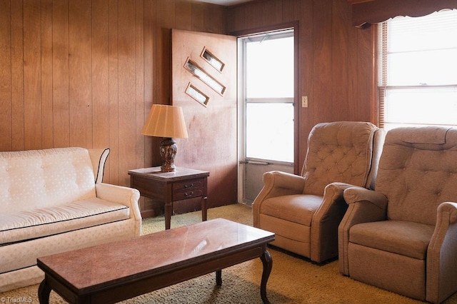 living area with a wealth of natural light, wood walls, and carpet