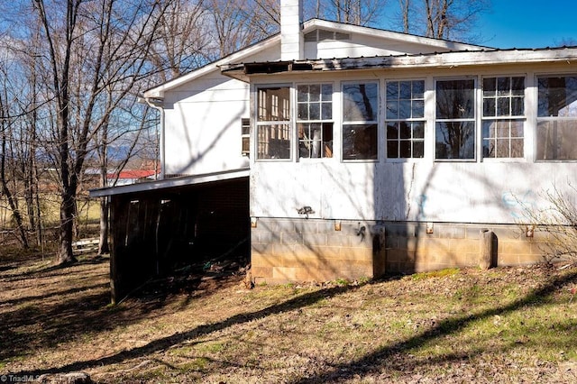 view of home's exterior with a chimney and metal roof