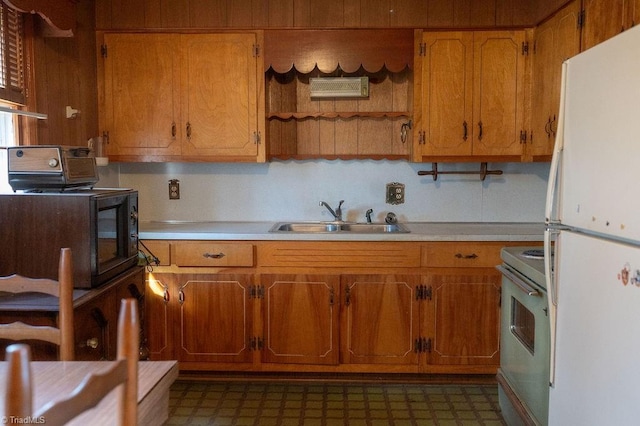 kitchen featuring freestanding refrigerator, light countertops, a sink, and electric range