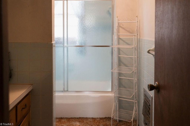 full bath featuring bath / shower combo with glass door, vanity, and tile walls