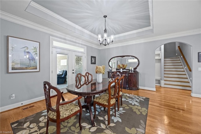 dining space with a tray ceiling, visible vents, a notable chandelier, and french doors