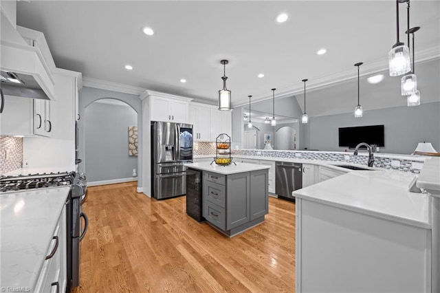 kitchen with a sink, white cabinetry, arched walkways, appliances with stainless steel finishes, and custom exhaust hood