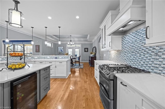 kitchen with ornamental molding, wine cooler, white cabinets, custom exhaust hood, and stainless steel range with gas stovetop