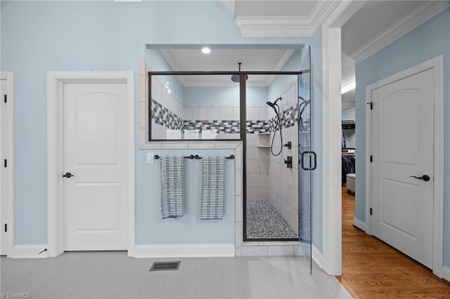 bathroom with visible vents, wood finished floors, a shower stall, crown molding, and baseboards