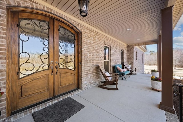 property entrance with brick siding, french doors, and covered porch