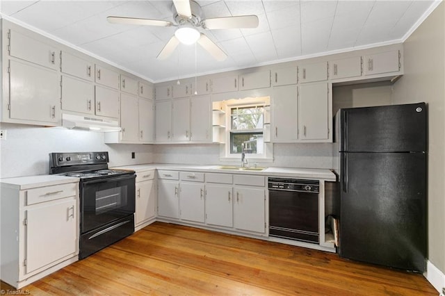 kitchen with light countertops, under cabinet range hood, a sink, and black appliances