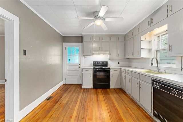 kitchen featuring ornamental molding, black appliances, under cabinet range hood, visible vents, and a sink