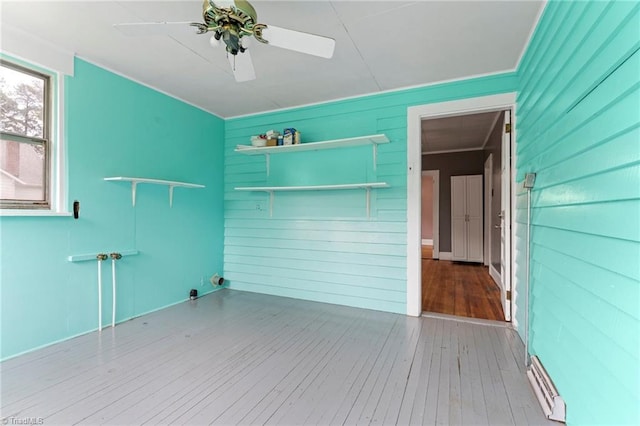 spare room featuring wood-type flooring, ceiling fan, and wood walls