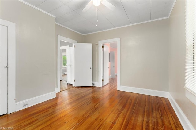 unfurnished room with ceiling fan, wood-type flooring, ornamental molding, and baseboards