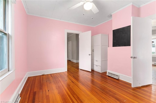 unfurnished bedroom featuring wood-type flooring, visible vents, baseboards, and crown molding