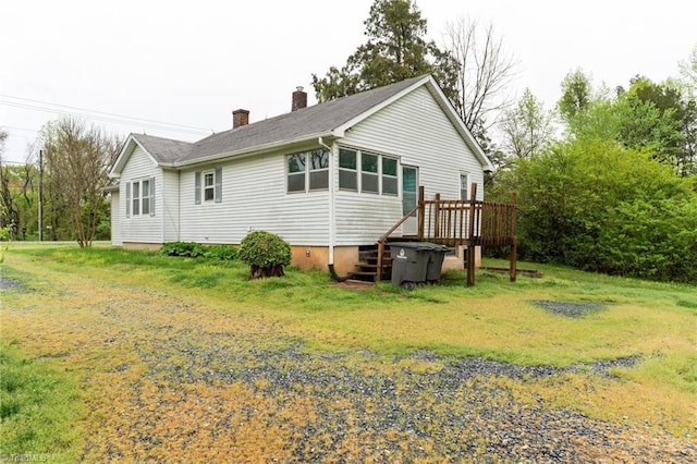 back of property featuring a deck, a lawn, and a chimney