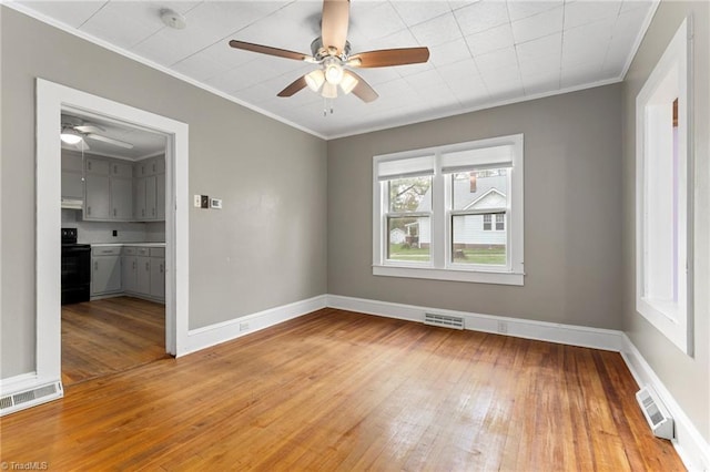 empty room featuring crown molding, a ceiling fan, visible vents, and light wood-type flooring