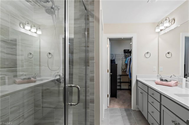 bathroom with a shower stall, tile patterned flooring, a walk in closet, and double vanity