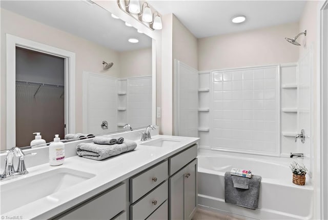 bathroom featuring double vanity, bathtub / shower combination, and a walk in closet