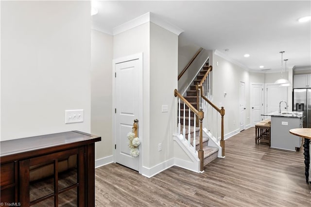 entryway featuring wood finished floors, baseboards, crown molding, stairs, and recessed lighting