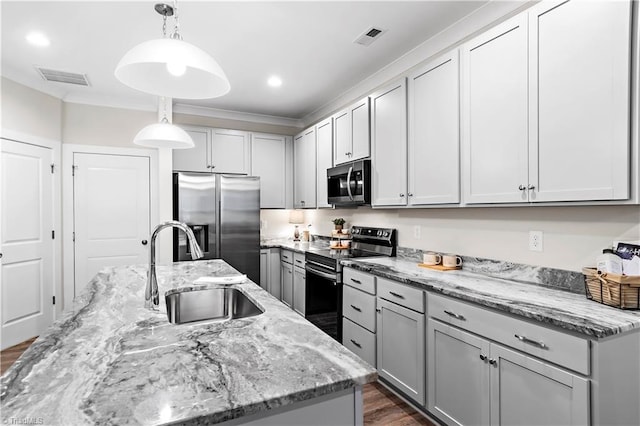 kitchen with appliances with stainless steel finishes, a sink, light stone countertops, a kitchen island with sink, and decorative light fixtures