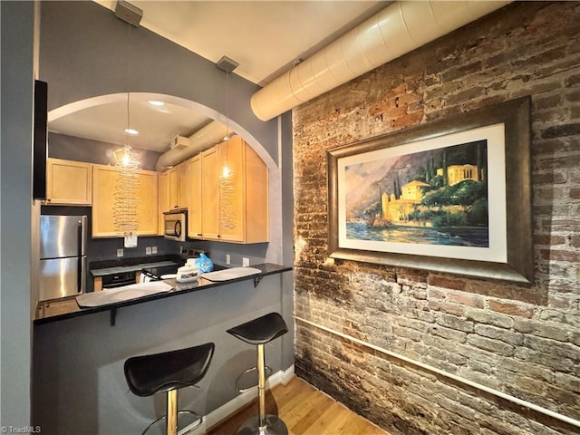 220 Market St Unit 110, Greensboro, NC 27401 - kitchen featuring stainless steel appliances, light brown cabinetry, dark countertops, wood finished floors, and arched walkways