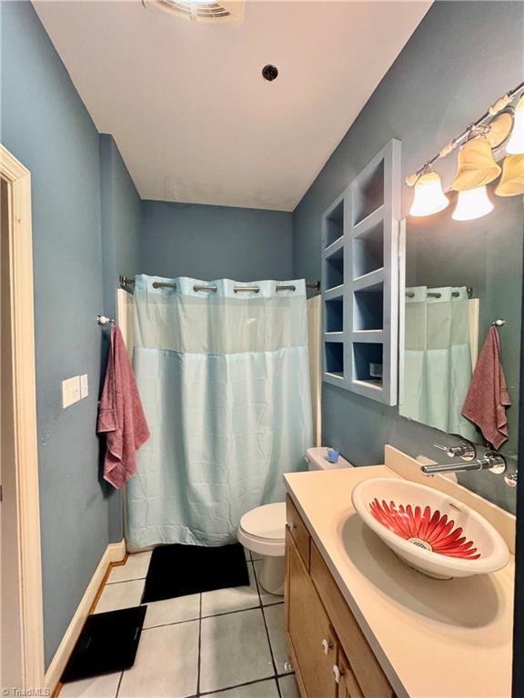 220 Market St Unit 110, Greensboro, NC 27401 - full bath with tile patterned flooring, vanity, curtained shower, and toilet